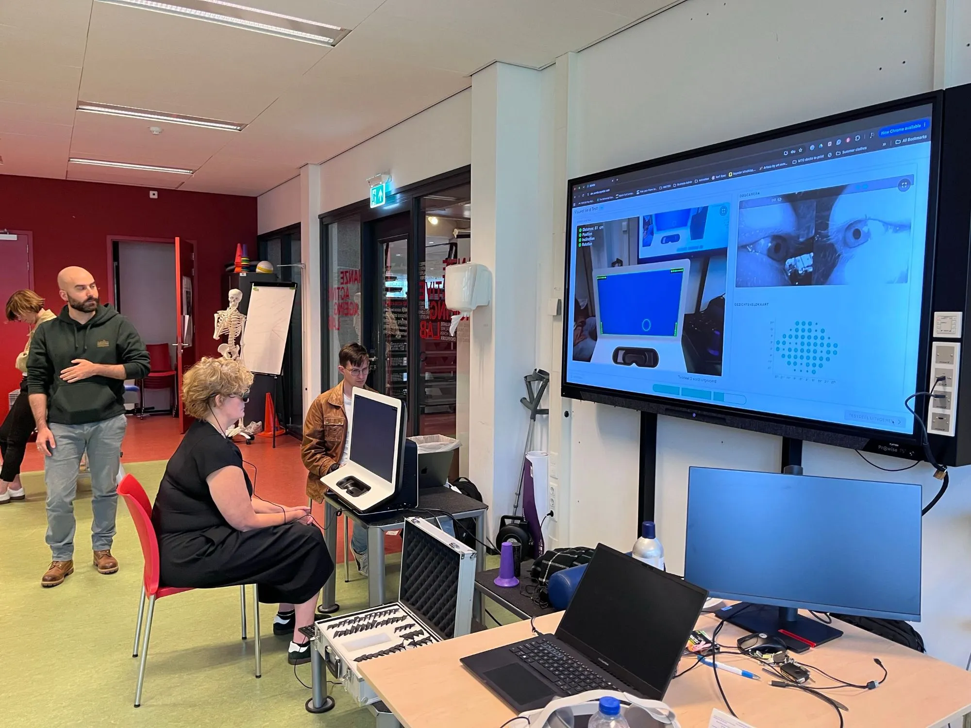 A visitor taking the SONDA test at the meetup, with the live eye-tracking view and the visual field map on the large screen behind